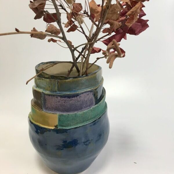 granatowy wazon ceramiczny z wielowarstwowymi szkliwami w odcieniach zieleni, granatu i fioletu.