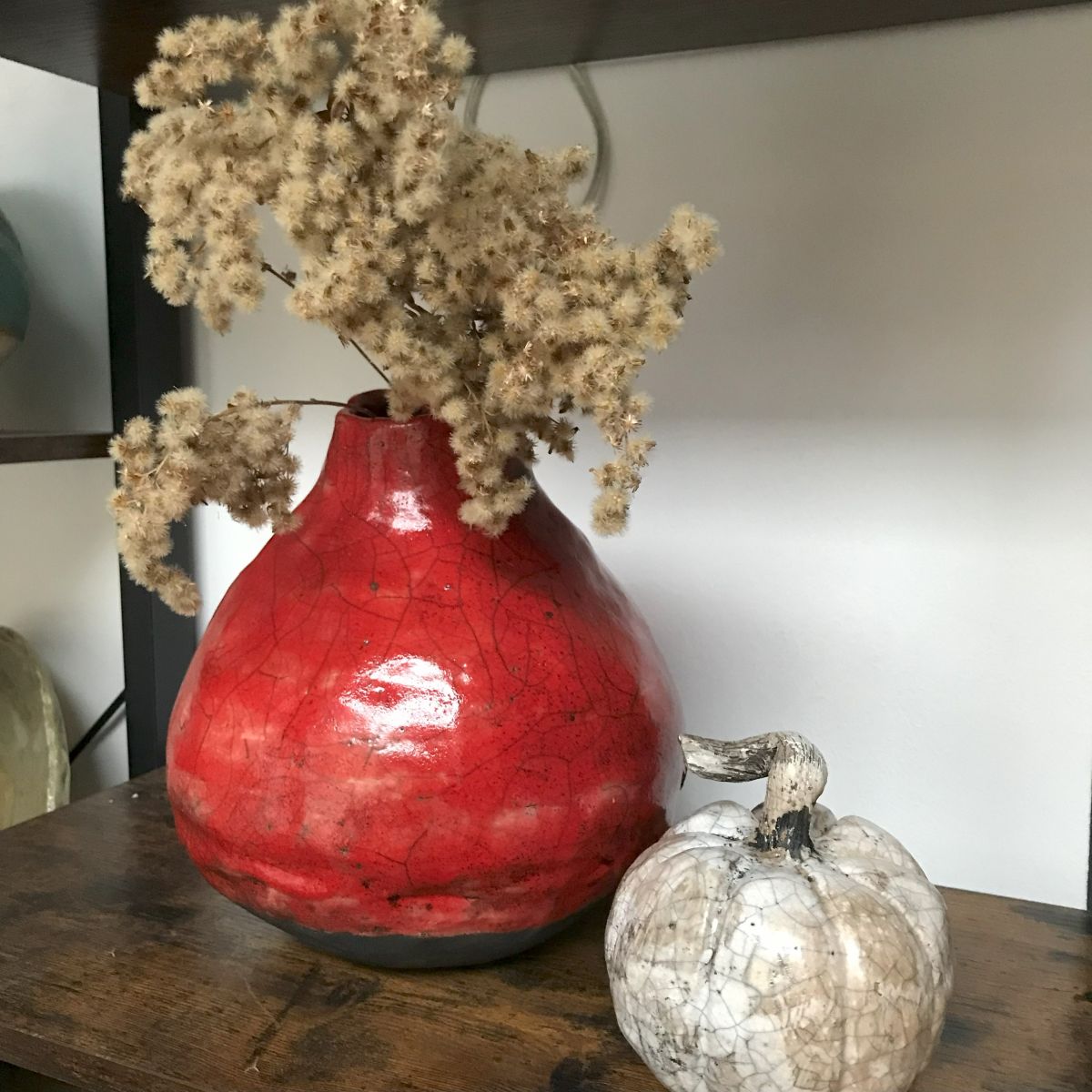 zerwona waza ceramiczna raku z suchą rośliną, obok mała dynia dekoracyjna – ceramika Merence