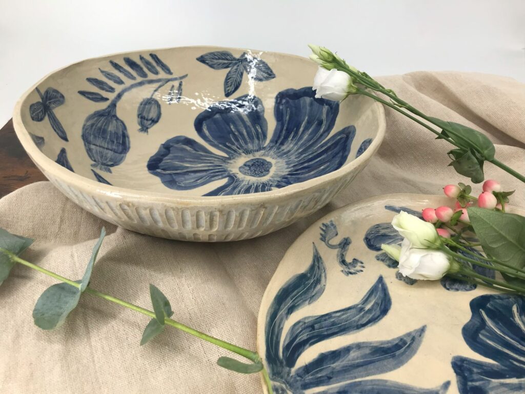 Duża misa ceramiczna z kobaltowym wzorem kwiatów, ułożona w aranżacji z lnianą tkaniną i kwiatami