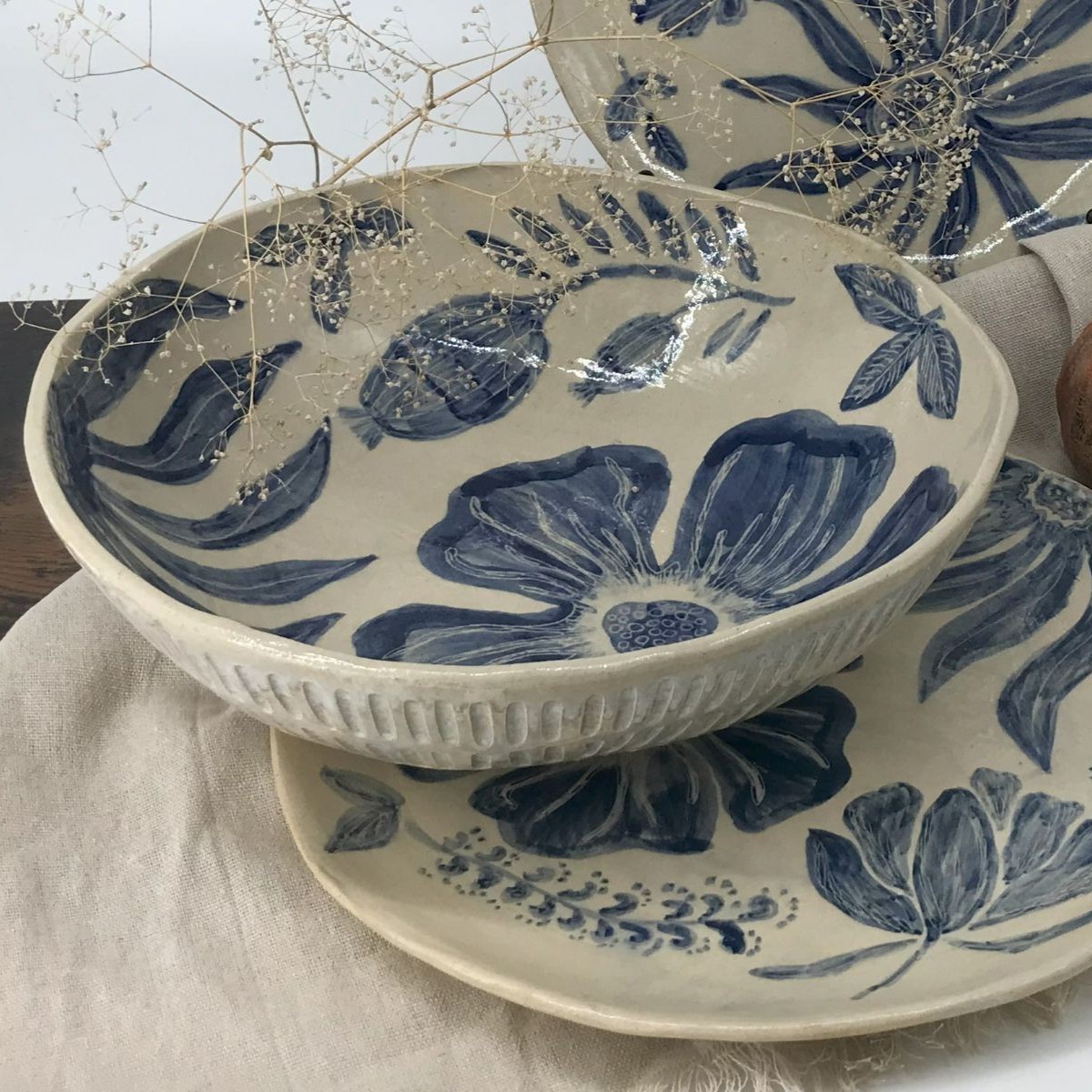 Duża misa ceramiczna z kwiatowym motywem malowanym w kobalcie, ustawiona na lnianej tkaninie
