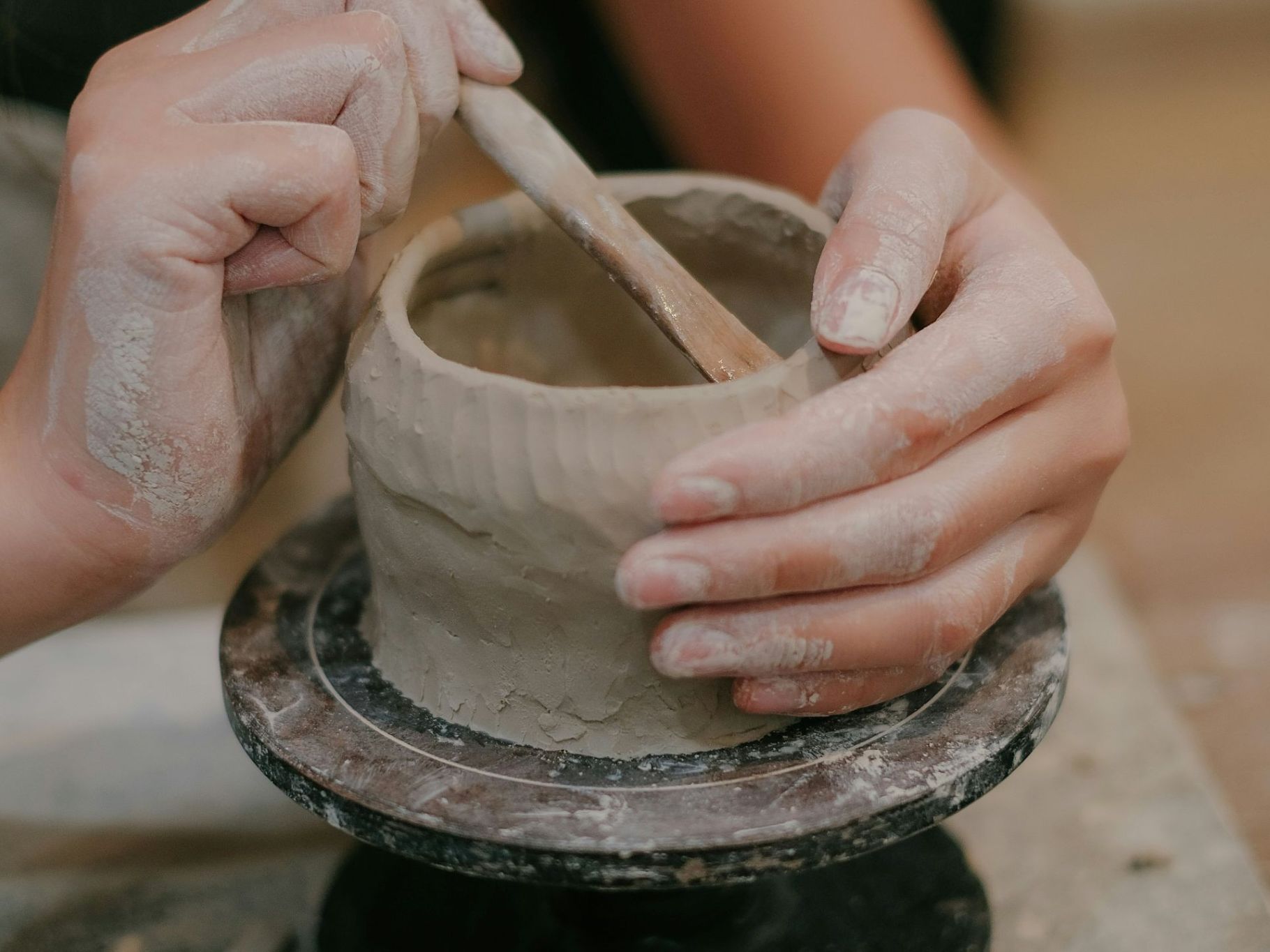Dłonie lepiące naczynie z gliny podczas warsztatów ceramiki dla dorosłych