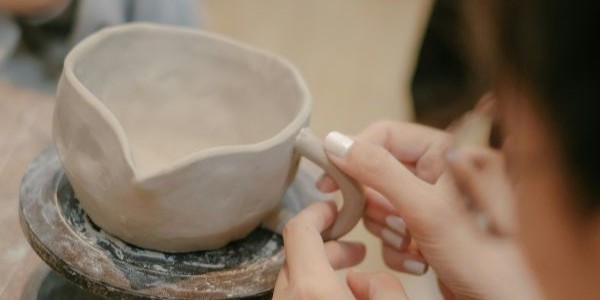 uczestniczka warsztatów ceramicznych modeluje uchwyt kubka