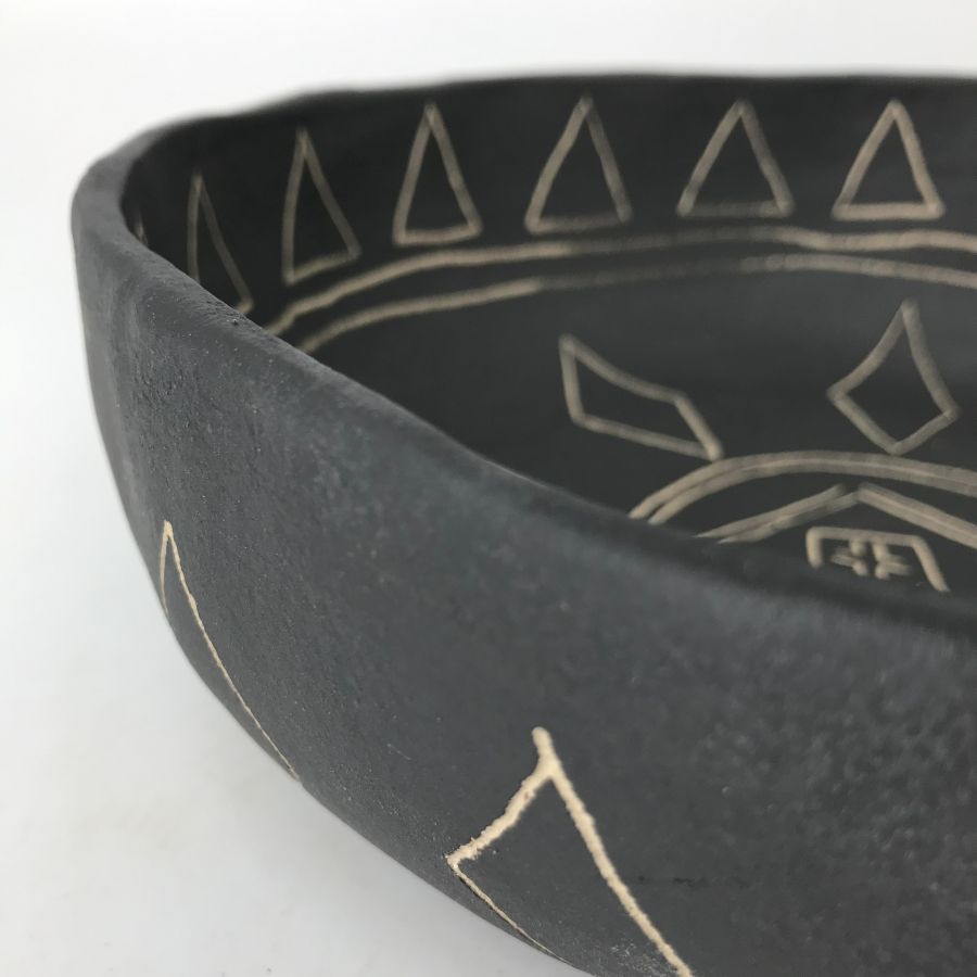 Zbliżenie krawędzi czarnej misy – faktura kamionki i nacięcia sgraffito.